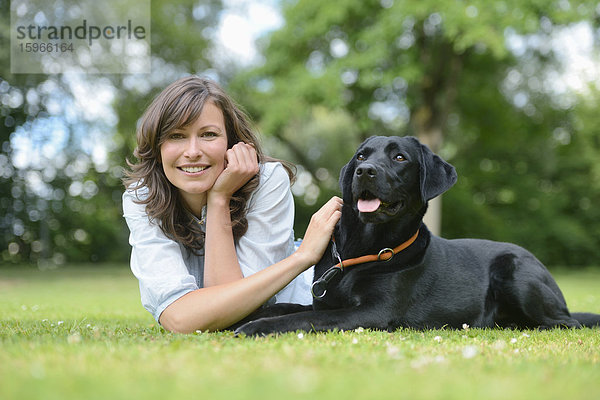 Frau mit einem schwarzen Labrador auf einer Wiese  Bayern  Deutschland  Europa