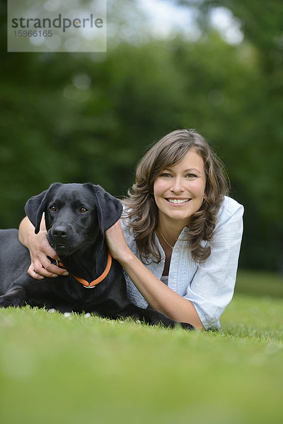 Frau mit einem schwarzen Labrador auf einer Wiese  Bayern  Deutschland  Europa