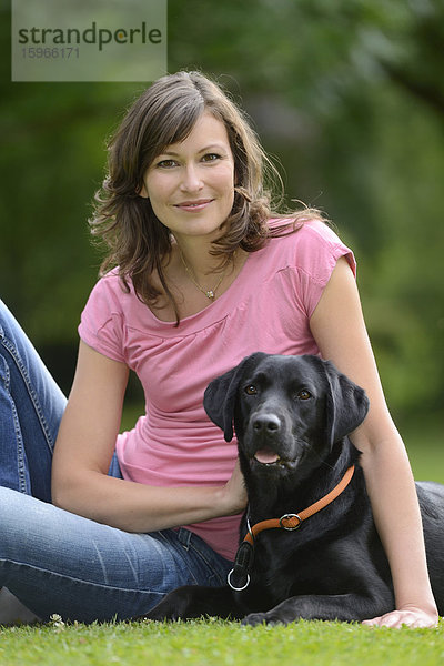 Frau mit einem schwarzen Labrador auf einer Wiese  Bayern  Deutschland  Europa