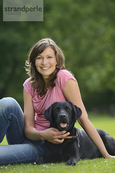 Frau mit einem schwarzen Labrador auf einer Wiese  Bayern  Deutschland  Europa