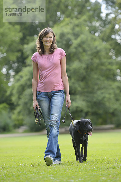 Frau mit einem schwarzen Labrador auf einer Wiese  Bayern  Deutschland  Europa