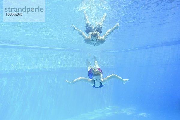 Ein Mann und ein Mädchen schwimmen unter Wasser in einem Freiluftbad