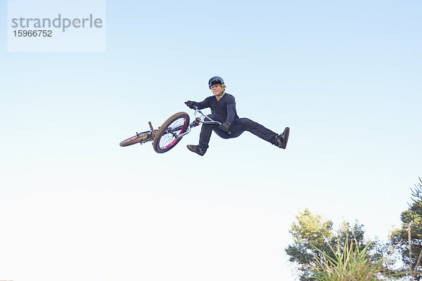 Teenager auf einem BMX-Rad springt in die Luft