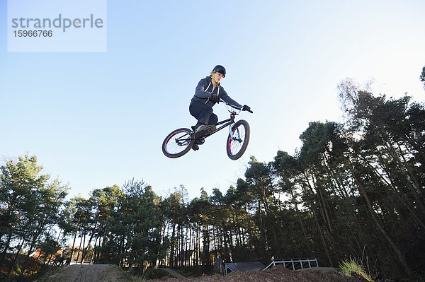 Teenager auf einem BMX-Rad springt in die Luft