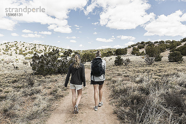 Rückansicht einer erwachsenen Frau und ihrer jugendlichen Tochter beim Wandern im Galisteo-Becken  NM.