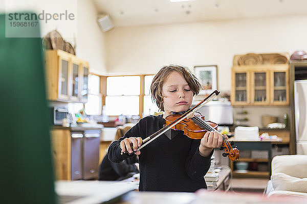 Sechsjähriger Junge  der Geige spielt und zu Hause eine ferngesteuerte Video-Unterrichtsstunde im Einschluss hat.