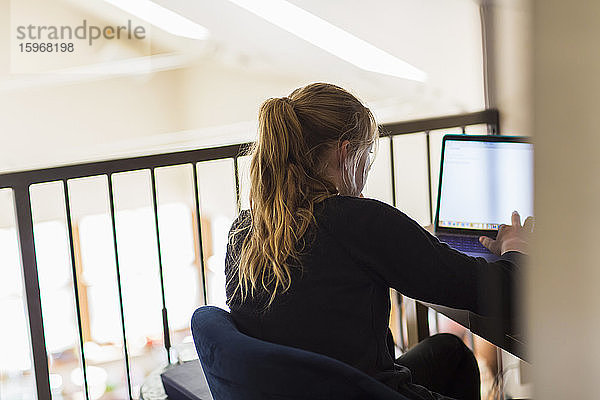 Teenagerin schaut zu Hause auf den Laptop