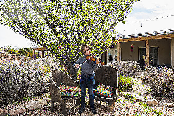 6-jähriger Junge spielt ausserhalb seines Hauses Geige