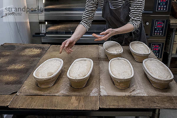 Handwerkliche Bäckerei  die spezielles Sauerteigbrot herstellt  ein Gestell mit Gärkörben voller aufgehender Teige.