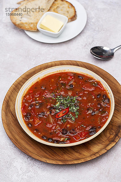 Nahaufnahme einer Tomaten- und Gemüsesuppe mit Beilage von Brot in einem Cafe.