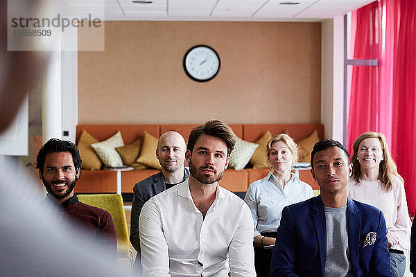 Männliche und weibliche Kollegen betrachten den Unternehmer bei einer Präsentation im Büroseminar