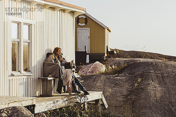 Sohn zeigt auf die Mutter  während er an einem sonnigen Tag vor der Kabine sitzt