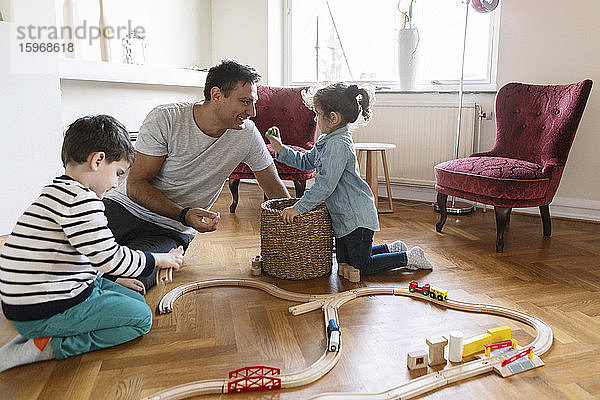 Spielerische Bindung der Tochter an den Vater  während der Bruder im Wohnzimmer spielt