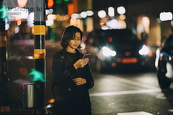 Textnachrichten von Frauen über Smartphones  die nachts in der Stadt stehen