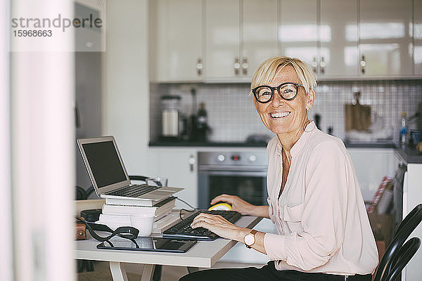 Porträt einer glücklichen Frau  die zu Hause arbeitet