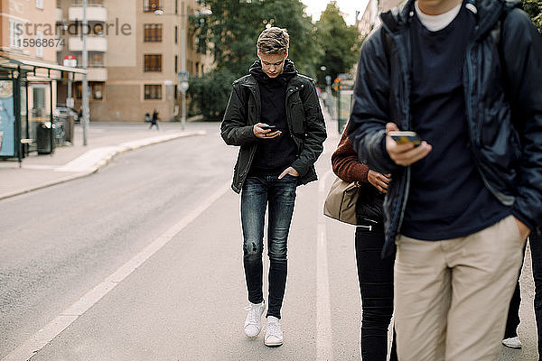 Teenager benutzt Smartphone beim Gehen auf der Straße in der Stadt