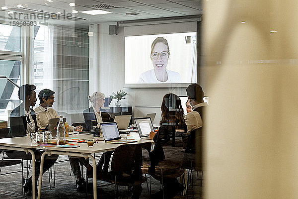 Geschäftskollegen bei Besprechung per Videokonferenz im Sitzungssaal am Arbeitsplatz