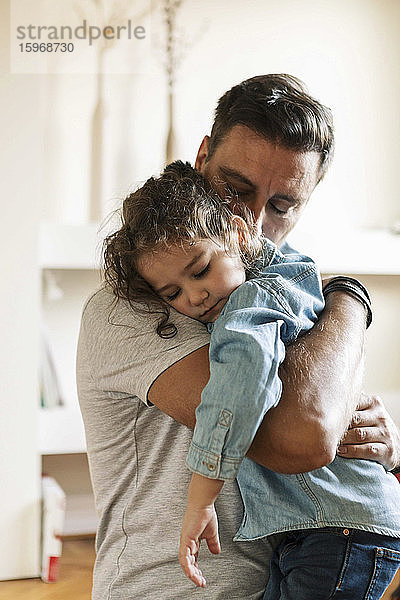 Vater umarmt traurige Tochter  während er zu Hause steht