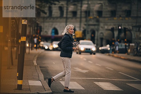 Ältere Frau schaut beim Überqueren einer Straße in der Stadt weg