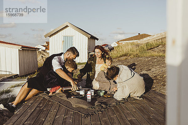 Familie mit Kindern sitzt im Sommer auf einer Decke vor der Hütte