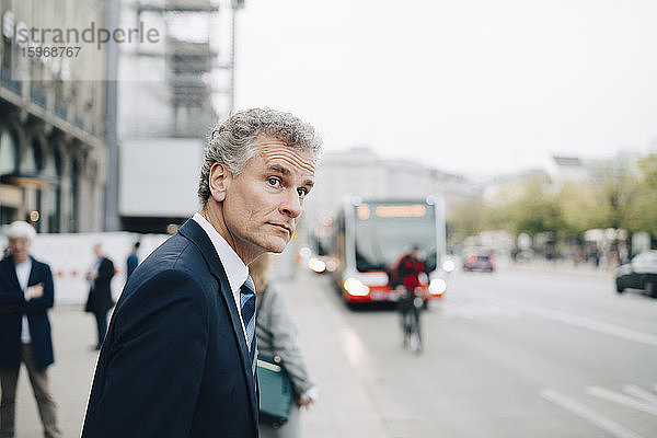 Reifer Geschäftsmann schaut weg  während er in der Stadt steht