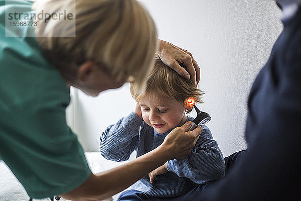 Ärztin untersucht im Krankenhaus das Ohr des Jungen mit dem Otoskop