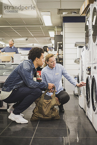Älterer Eigentümer erklärt männlichen Kunden im Elektronikgeschäft über Waschmaschine