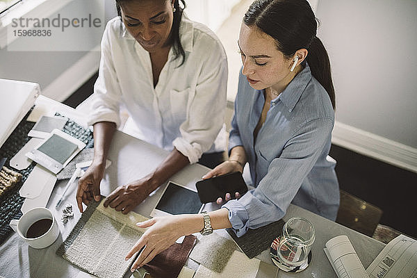 Hochwinkelansicht von Designerinnen  die im Heimbüro am Tisch sitzen