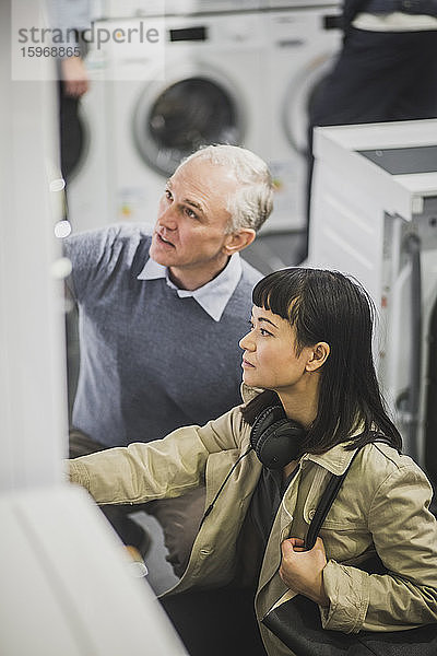 Hochwinkelansicht des männlichen Besitzers und der weiblichen Kundin im Elektronikgeschäft