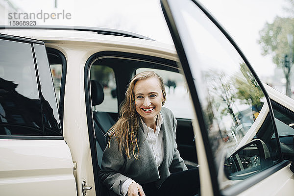 Lächelnde Unternehmerin steigt während einer Geschäftsreise aus dem Taxi