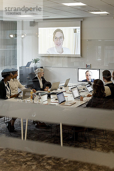 Geschäftsleute diskutieren während einer globalen Konferenz in einer Vorstandssitzung im Büro