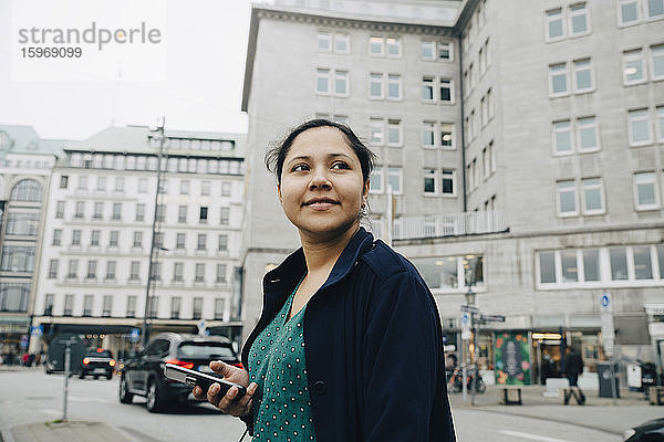 Seitenansicht einer selbstbewussten Unternehmerin mit Telefonstand in der Stadt