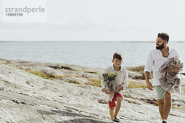 Lächelnder Vater hält Decke  während er sich im Sommer mit seinem Sohn verbindet