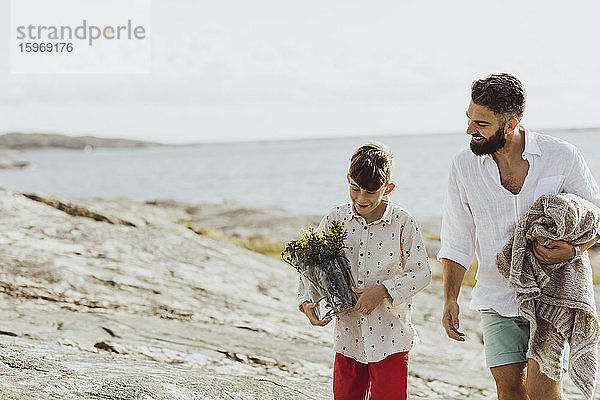 Lächelnder Vater hält Decke  während er sich während der Sommerferien mit seinem Sohn verbindet