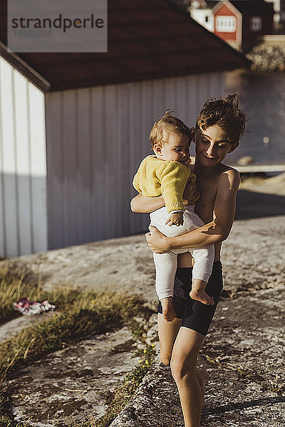 Lächelnder Bruder trägt kleine Schwester beim Spaziergang auf dem Archipel