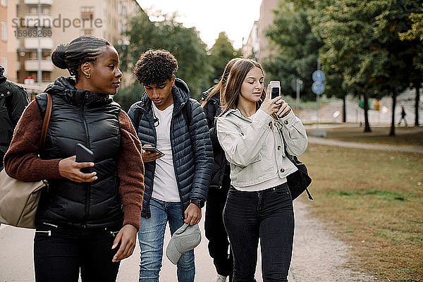 Mädchen und Jungen im Teenageralter telefonieren auf der Straße in der Stadt