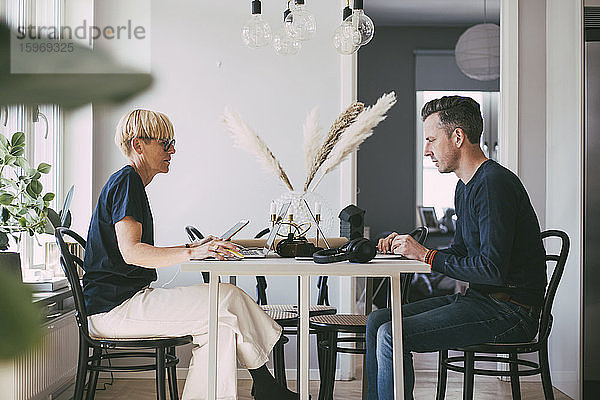 Profil von Frau und Mann bei Tisch  die von zu Hause aus arbeiten