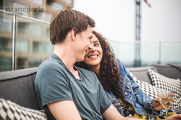 Lächelnder Mann mit Partnerin auf der Terrasse beim geselligen Beisammensein