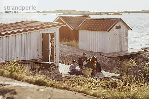 Hochwinkelansicht einer Familie mit Kindern  die im Sommer vor der Hütte sitzen