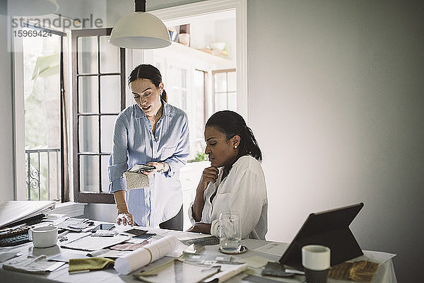 Architektinnen diskutieren über Stoffmuster bei der Arbeit am Tisch im Home-Office