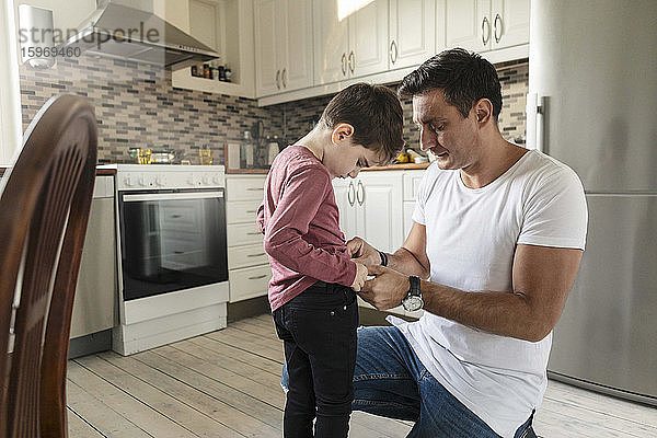 Vater verkleidet Sohn  während er auf dem Küchenboden kniet