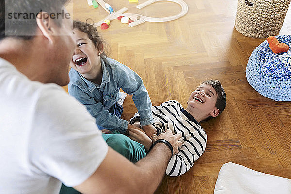 Hochwinkelaufnahme eines Vaters  der zu Hause mit Kindern spielt