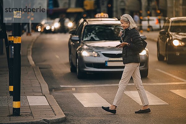 Ältere Frau geht auf Zebrastreifen in der Stadt