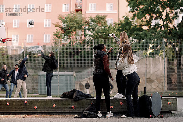 Teenager-Mädchen in voller Länge  die sich im Park per Smartphone selbstständig machen