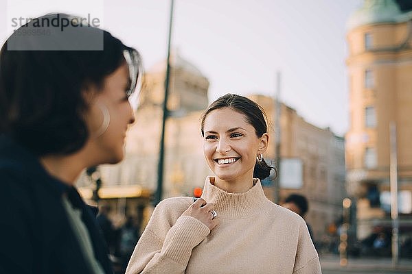Lächelnde junge Frau schaut eine Freundin in der Stadt an