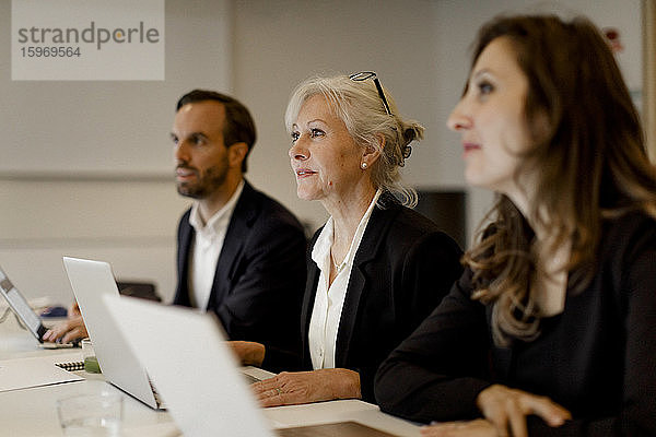 Männliche und weibliche Führungskräfte verwenden Laptops am Konferenztisch bei Bürobesprechungen