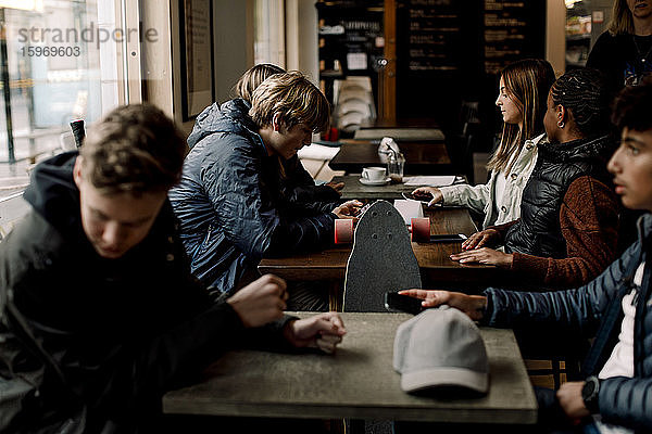 Multiethnische Freunde im Teenageralter sitzen in einem Café am Tisch