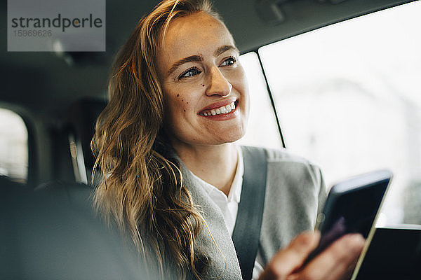 Zuversichtlich lächelnder Unternehmer schaut weg  während er im Taxi sitzt