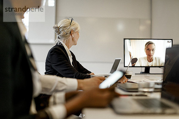 Geschäftsfrau nimmt an Videokonferenz mit Kollegen in Bürobesprechung teil