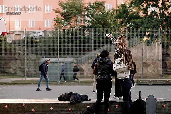 Teenager-Mädchen nimmt sich mit Freundinnen per Handy im Stadtpark mit